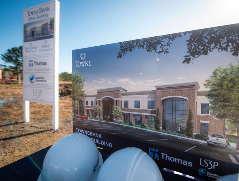 Photo of building rendering and hard hats at groundbreaking event.